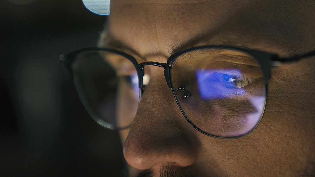 A man straining his eyes by staring at a screen closely